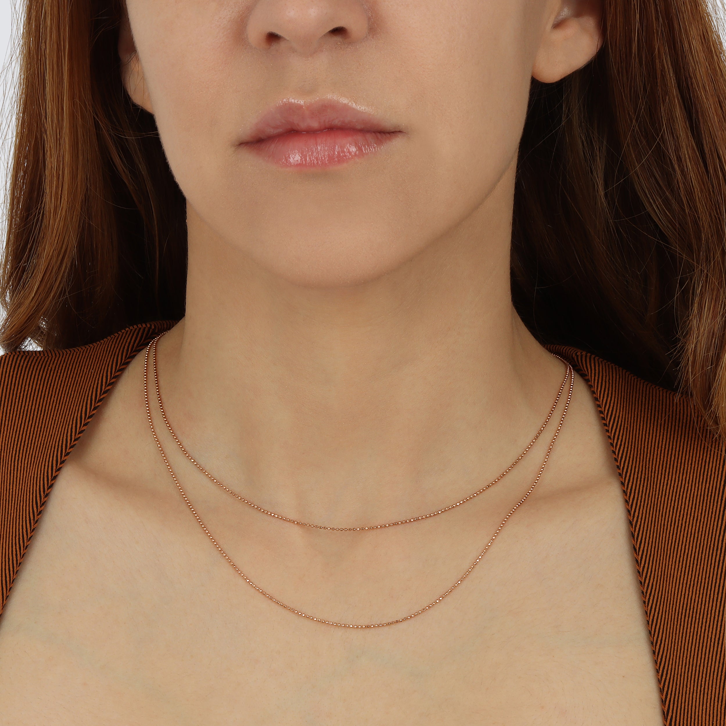 a model wearing a 1.0mm franco ball chain in yellow gold available in 14k.  highly polished chain.