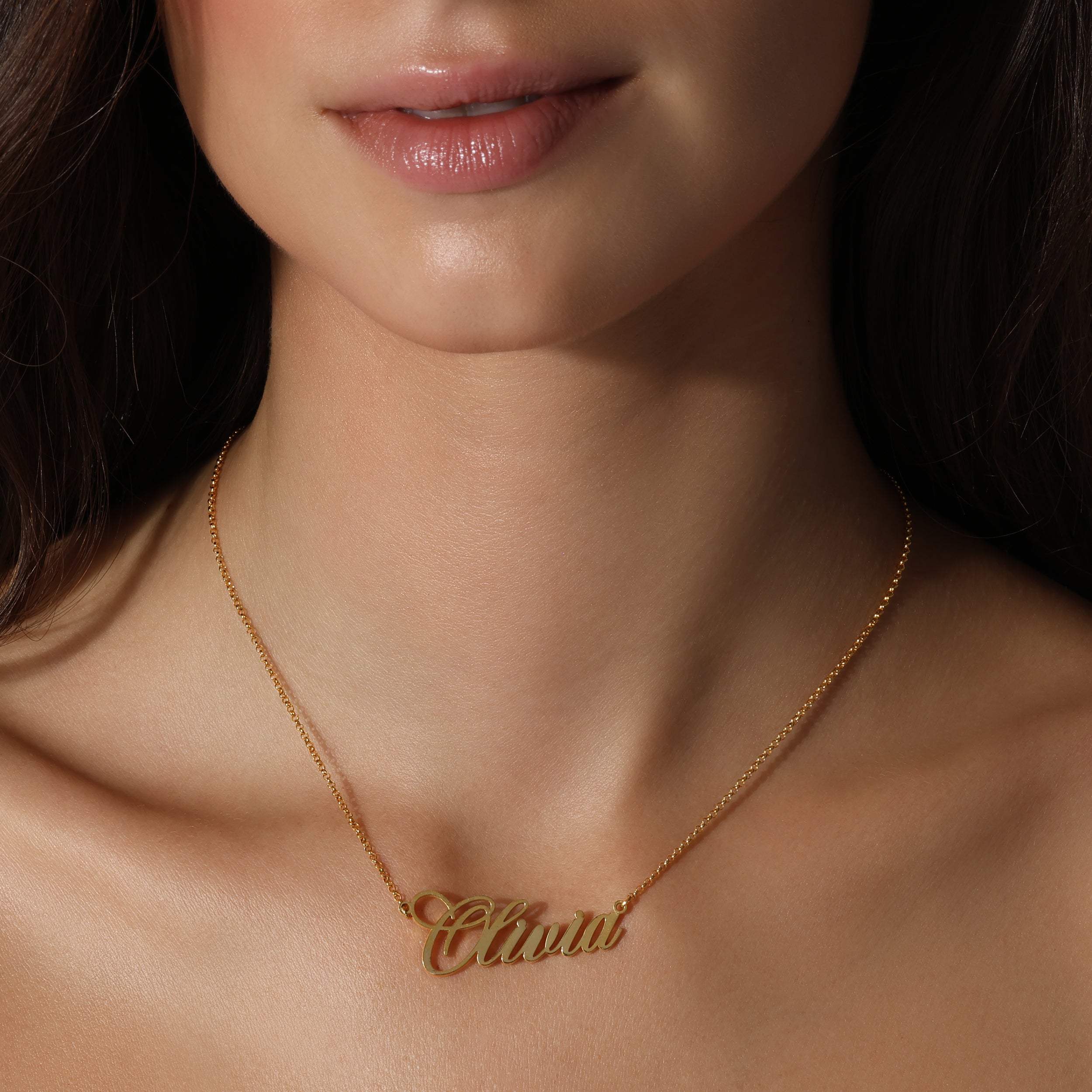 girl wearing solid gold nameplate olivia necklace smooth pale skin dark hair closeup jewelry shot